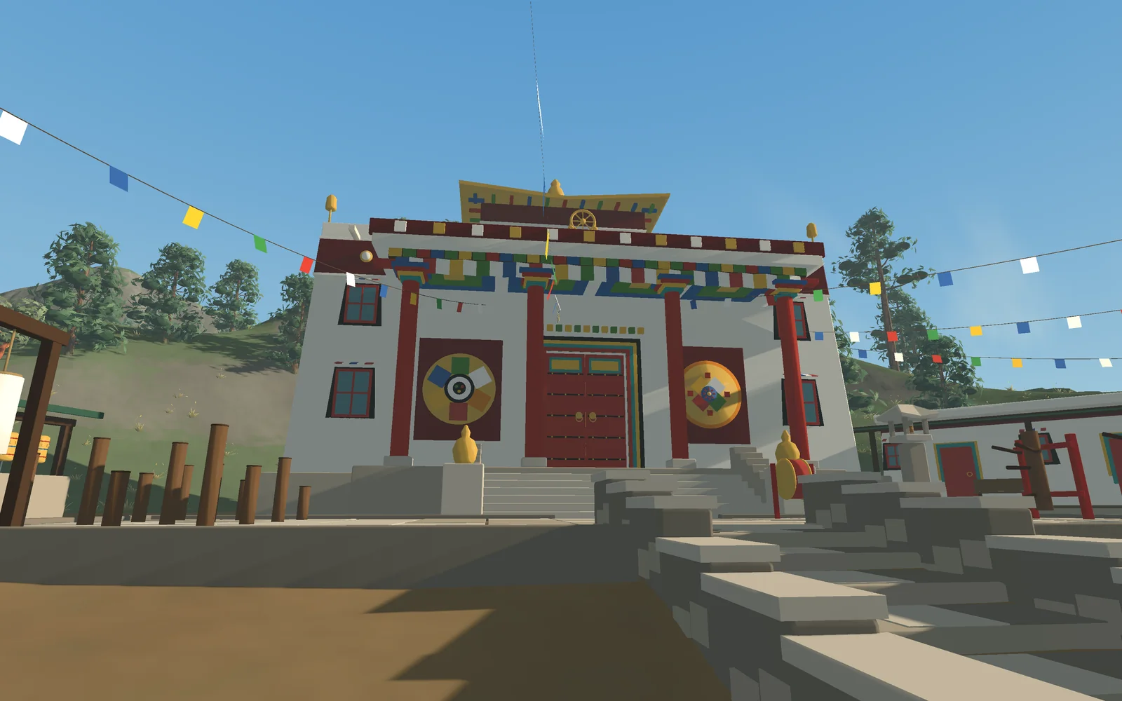 The temple's white hall with its painted frieze and prayer flags, on a terrace in the sierra